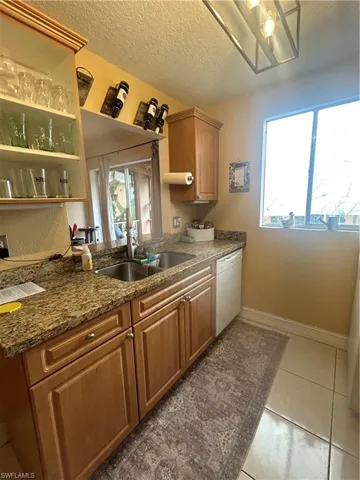 Kitchen featuring tile floors, sink, dishwasher, and a textured ceiling