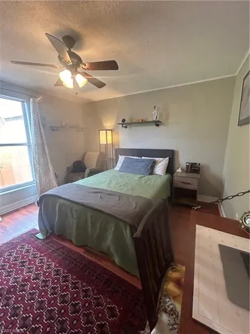 Bedroom featuring wood-type flooring, ceiling fan, and a textured ceiling