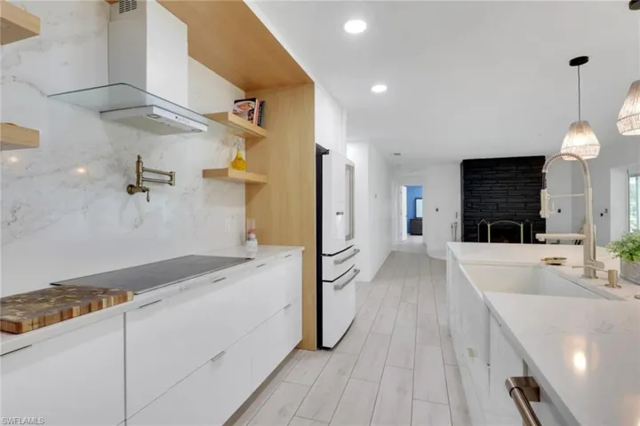 Modern kitchen featuring white flat-panel cabinetry, a built-in induction cooktop, and a matching white range hood