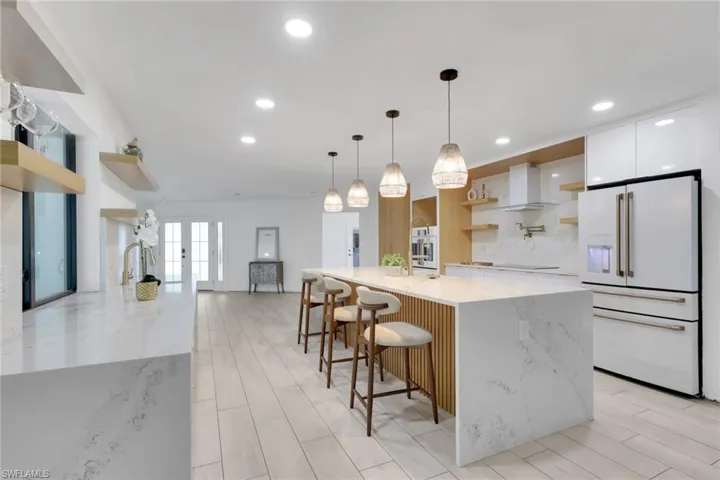 Contemporary kitchen featuring a spacious island with seating, integrated appliances, and light wood-finish flooring