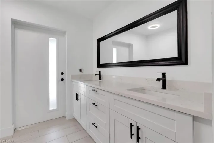Dual vanity featuring light-toned countertops, integrated sinks, and matte black fixtures
