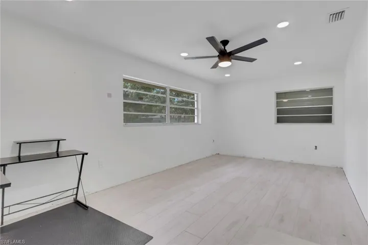 Spacious room featuring light wood-finish flooring, recessed lighting, and a contemporary ceiling fan