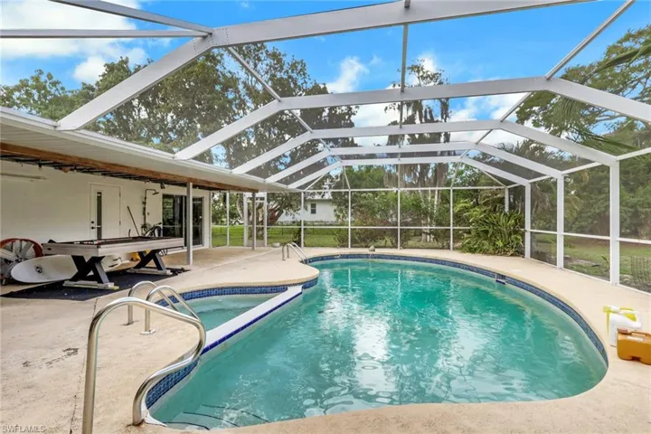 Screened enclosure featuring a freeform swimming pool and integrated spa