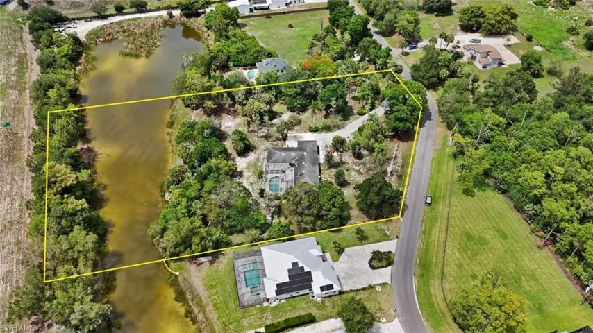 Expansive property featuring a private water frontage, lush landscaping, mature trees, and a private driveway