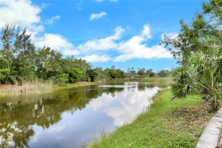 Waterfront property featuring a tranquil waterway, lush green grasses, and mature trees