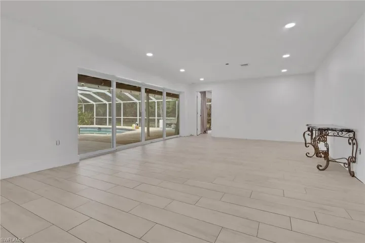 Spacious interior featuring light-toned plank flooring, recessed lighting, and expansive sliding glass doors