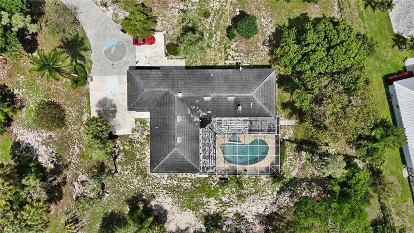 Residential property featuring a screened-in swimming pool, a circular drive, and a gabled roof