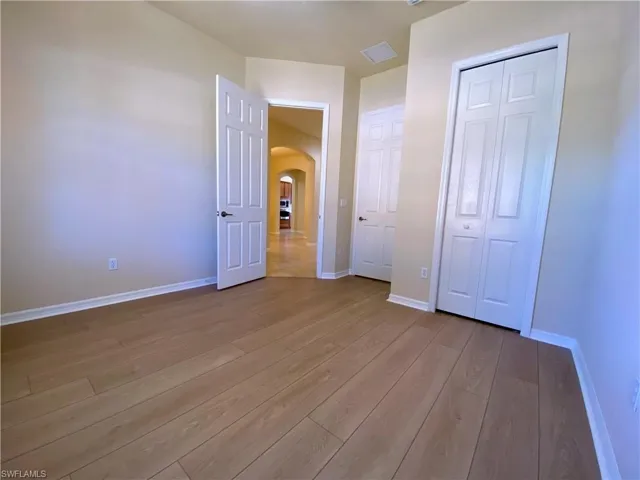 Unfurnished bedroom featuring arched walkways, hardwood / wood-style floors, and a closet