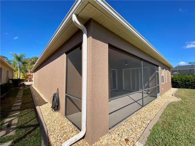 View of home's exterior with stucco siding, a sunroom, a lanai, and a yard