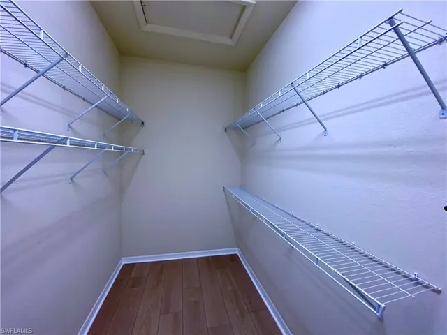 Spacious closet with dark wood-style flooring and attic access