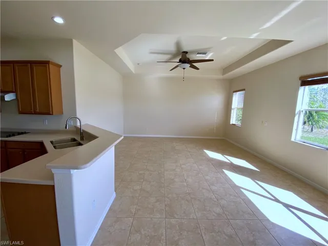 Kitchen with a tray ceiling, brown cabinets, light countertops, and a peninsula