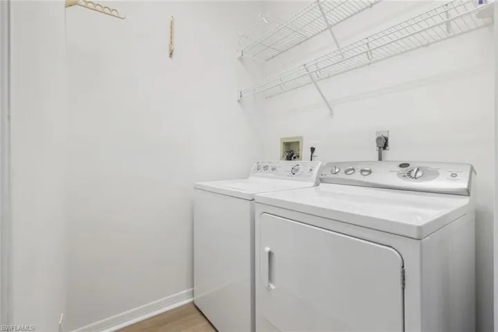 Laundry room with washer and clothes dryer, baseboards, and light wood-style flooring