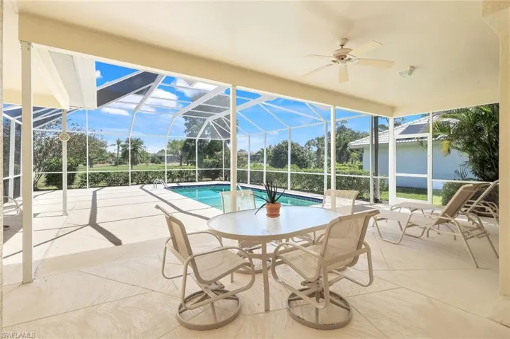 Outdoor pool with ceiling fan, a patio area, and glass enclosure
