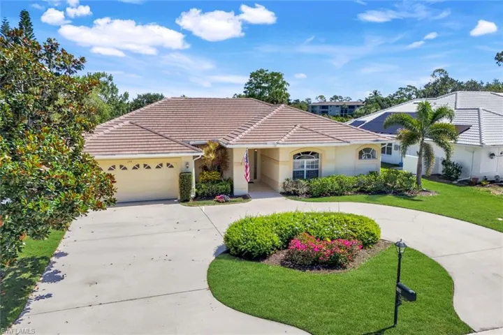 View of front of house featuring curved driveway, stucco siding, a front lawn, a garage, and a tiled roof