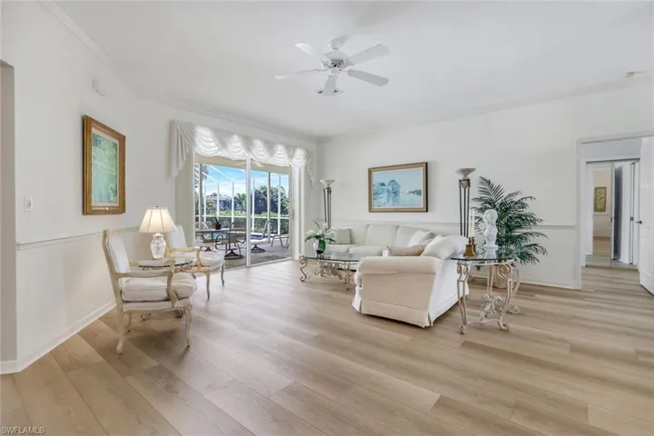 Living area with light wood-style floors, ceiling fan, crown molding, and baseboards