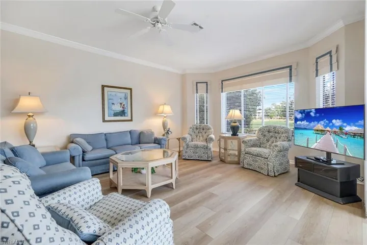 Living area featuring ornamental molding, light wood-style flooring, and a ceiling fan