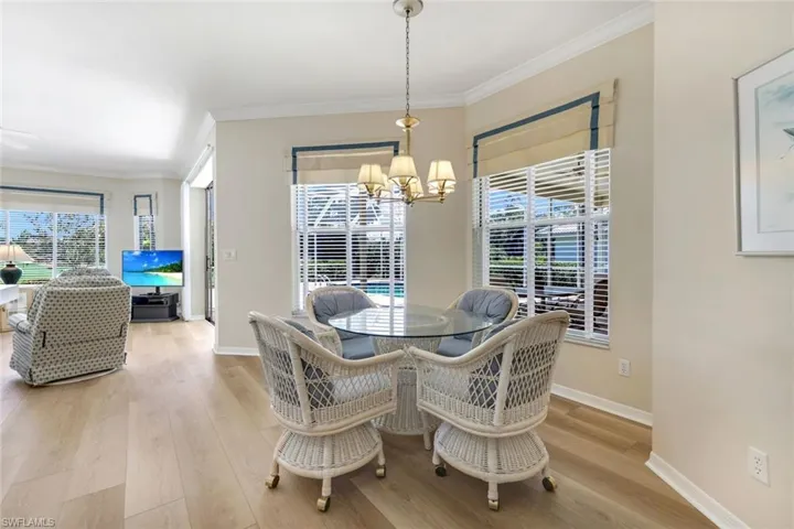 Dining area with a chandelier, wood finished floors, baseboards, and crown molding