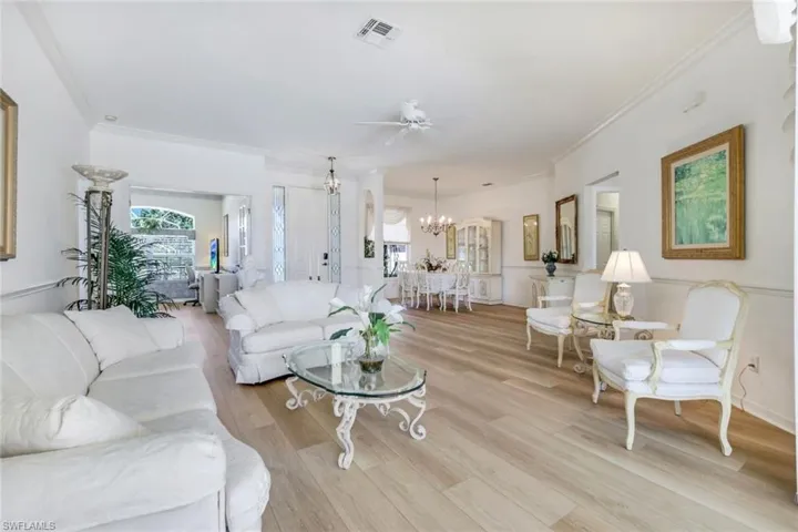 Living room with a chandelier, plenty of natural light, crown molding, ceiling fan, and light wood finished floors