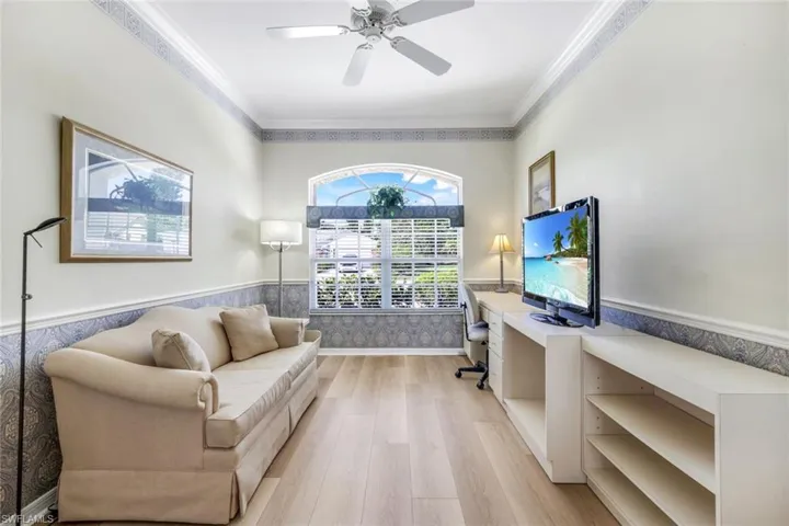 Office area featuring wainscoting, light wood-type flooring, crown molding, and a ceiling fan