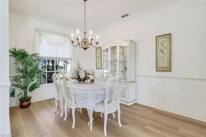 Dining area with a chandelier, light wood finished floors, ornamental molding, and baseboards