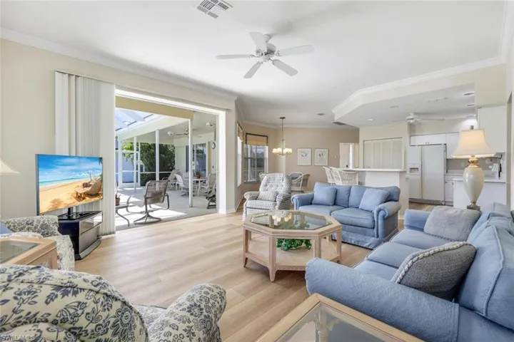 Living room with ceiling fan, ornamental molding, and light wood-type flooring