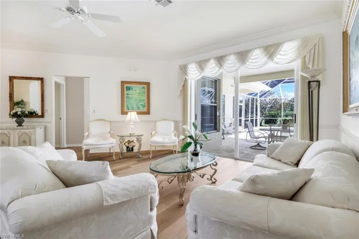 Living area featuring light wood-style floors, ornamental molding, a ceiling fan, and a sunroom