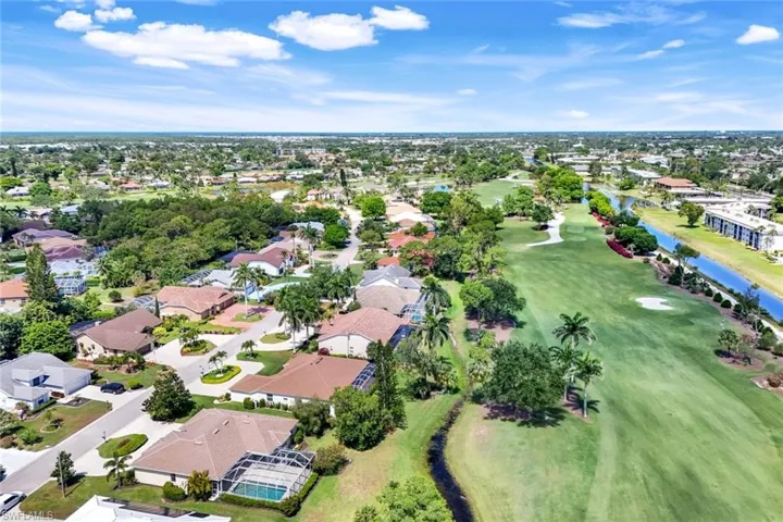 Aerial view of property's location with a nearby body of water, a local golf course, and nearby suburban area