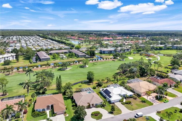 View of property location featuring a local golf course, nearby suburban area, and a nearby body of water