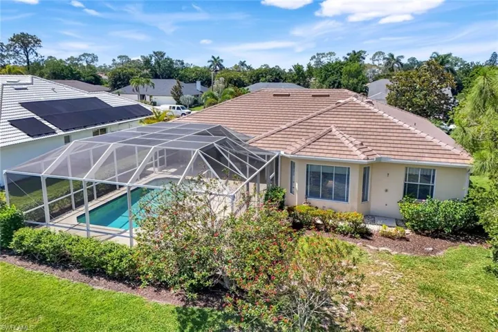 Rear view of property with a tile roof, glass enclosure, an outdoor pool, stucco siding, and a yard
