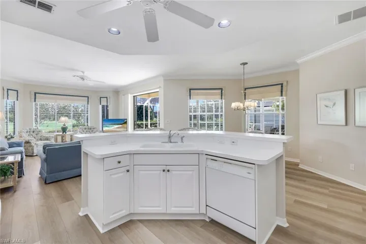 Kitchen featuring dishwasher, a sink, open floor plan, ceiling fan, and crown molding