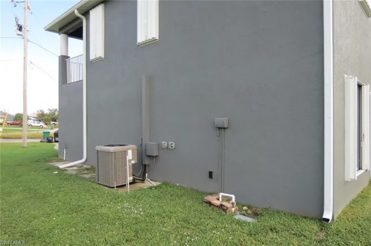 View of side of property featuring central AC unit and a lawn