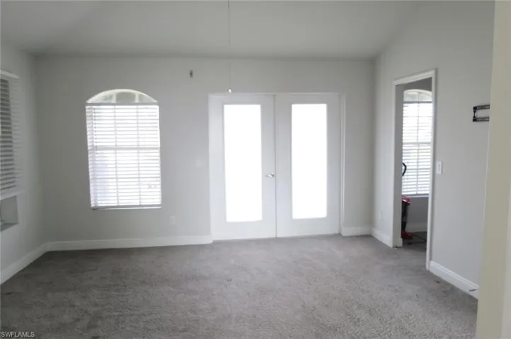Empty room with vaulted ceiling, carpet flooring, and french doors