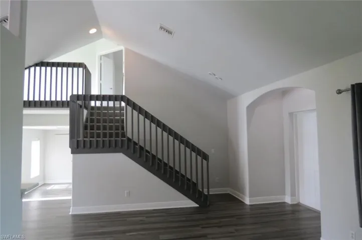 Stairs with wood-type flooring and lofted ceiling