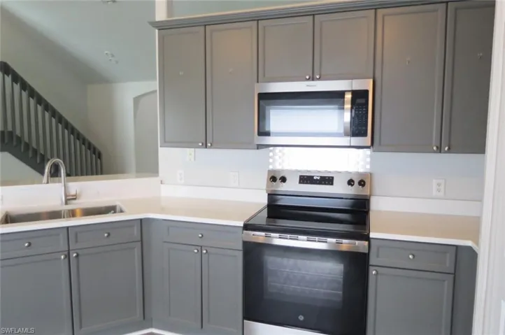Kitchen with gray cabinets, appliances with stainless steel finishes, and sink