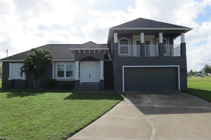 View of front of house with a garage, a front yard, and a balcony