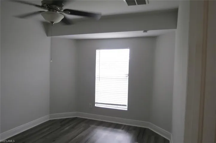 Spare room featuring dark wood-type flooring and ceiling fan