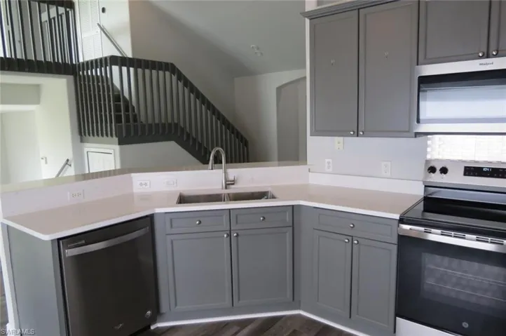 Kitchen featuring gray cabinetry, kitchen peninsula, appliances with stainless steel finishes, and sink