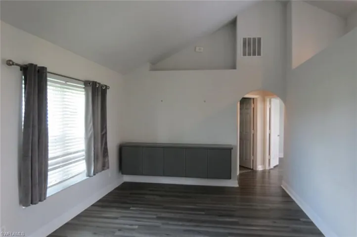 Spare room featuring high vaulted ceiling and dark hardwood / wood-style flooring