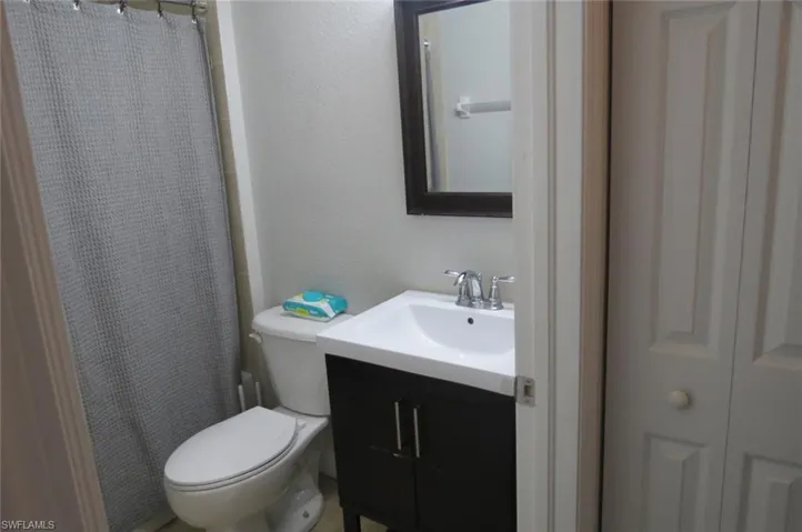 Bathroom with toilet, vanity, and a shower with shower curtain