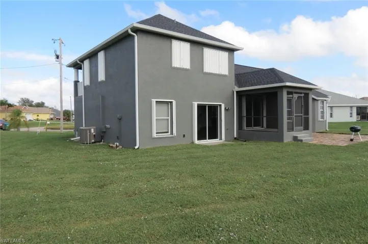 Rear view of house with a sunroom, a lawn, and cooling unit