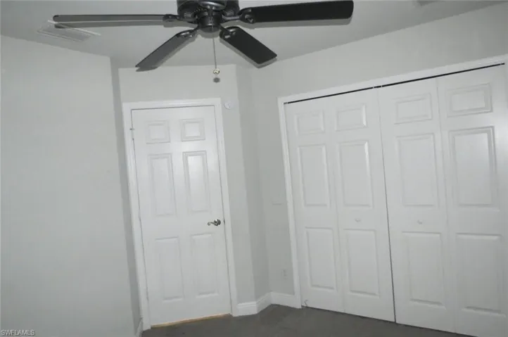 Unfurnished bedroom with ceiling fan and a closet