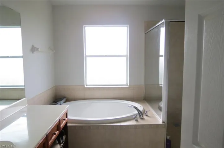 Bathroom featuring shower with separate bathtub and vanity