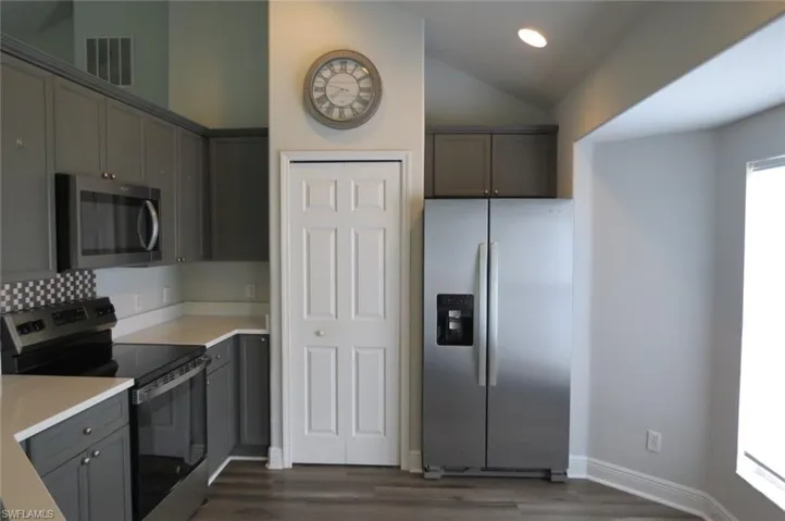 Kitchen featuring stainless steel appliances, dark hardwood / wood-style floors, vaulted ceiling, and gray cabinetry