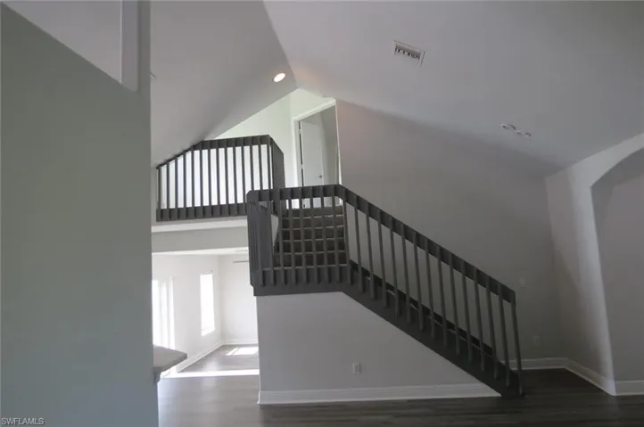 Staircase with wood-type flooring and lofted ceiling