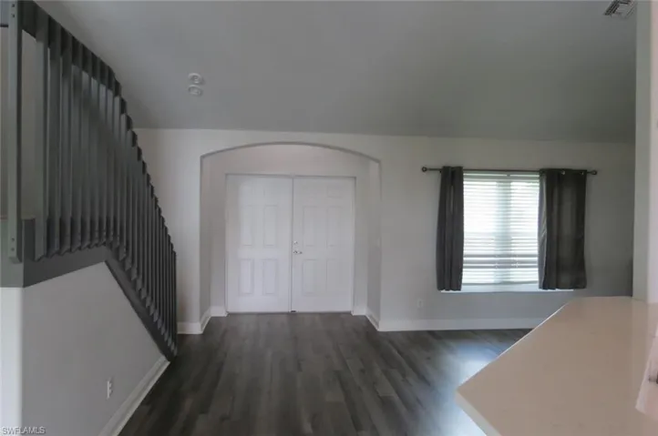 Foyer entrance featuring dark wood-type flooring and vaulted ceiling