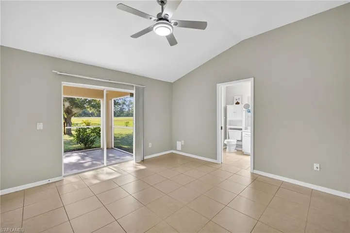 Spare room featuring vaulted ceiling, light tile patterned floors, and a ceiling fan