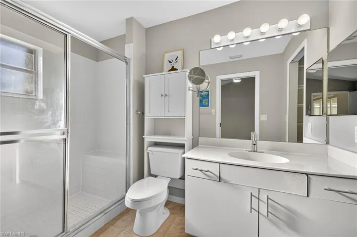 Full bath with vanity, a shower stall, and light tile patterned flooring