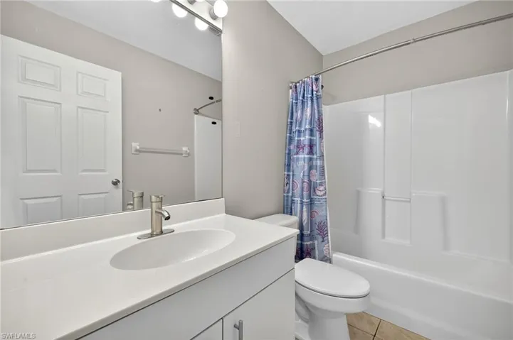 Full bathroom featuring shower / bath combination with curtain, light tile patterned flooring, and vanity