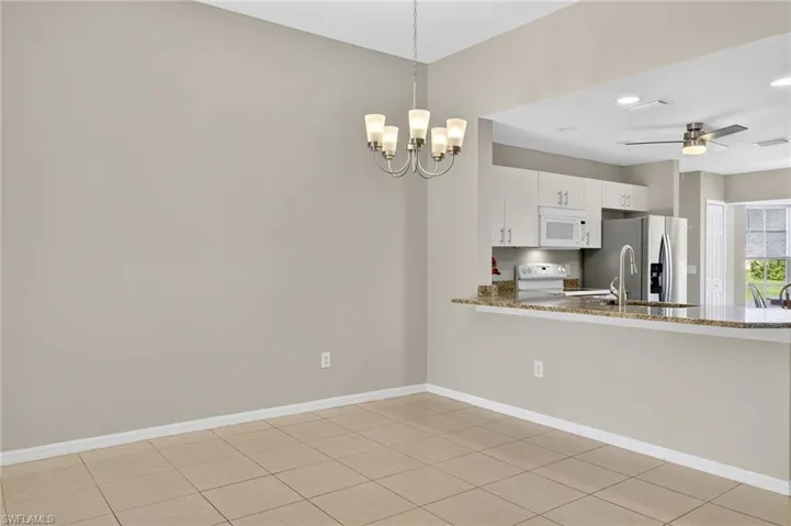Kitchen featuring pendant lighting, a ceiling fan, light stone countertops, white cabinetry, and white appliances