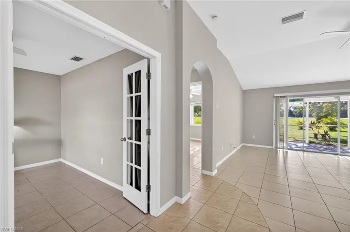 Spare room featuring a ceiling fan, light tile patterned flooring, arched walkways, healthy amount of natural light, and lofted ceiling